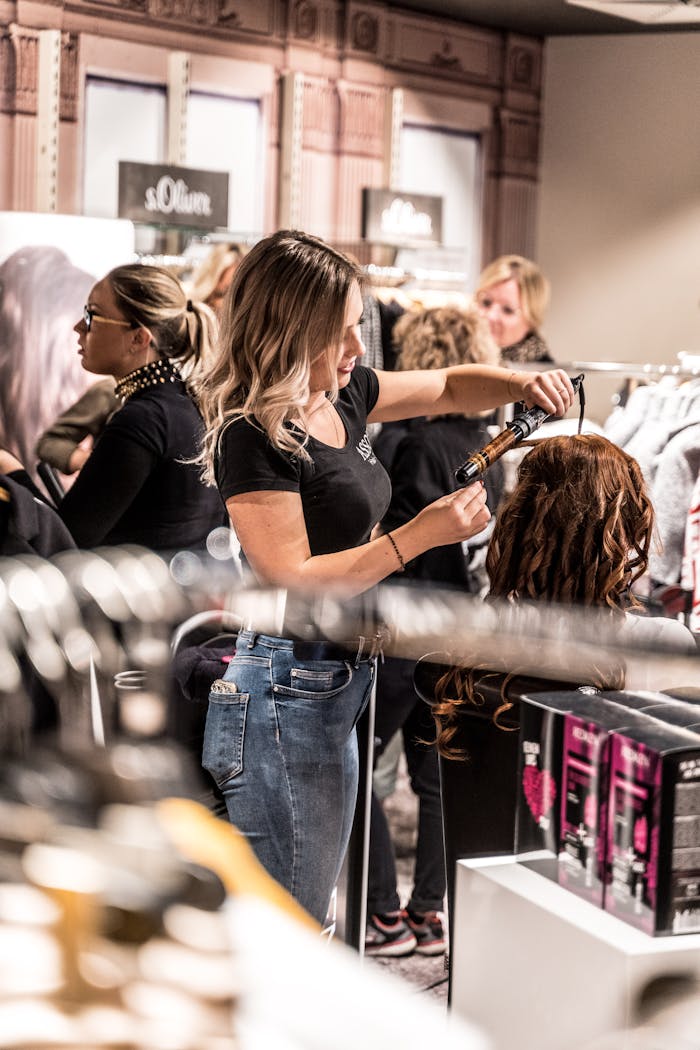 digital A skilled hairstylist uses a curling iron to style a client's hair in a busy salon.