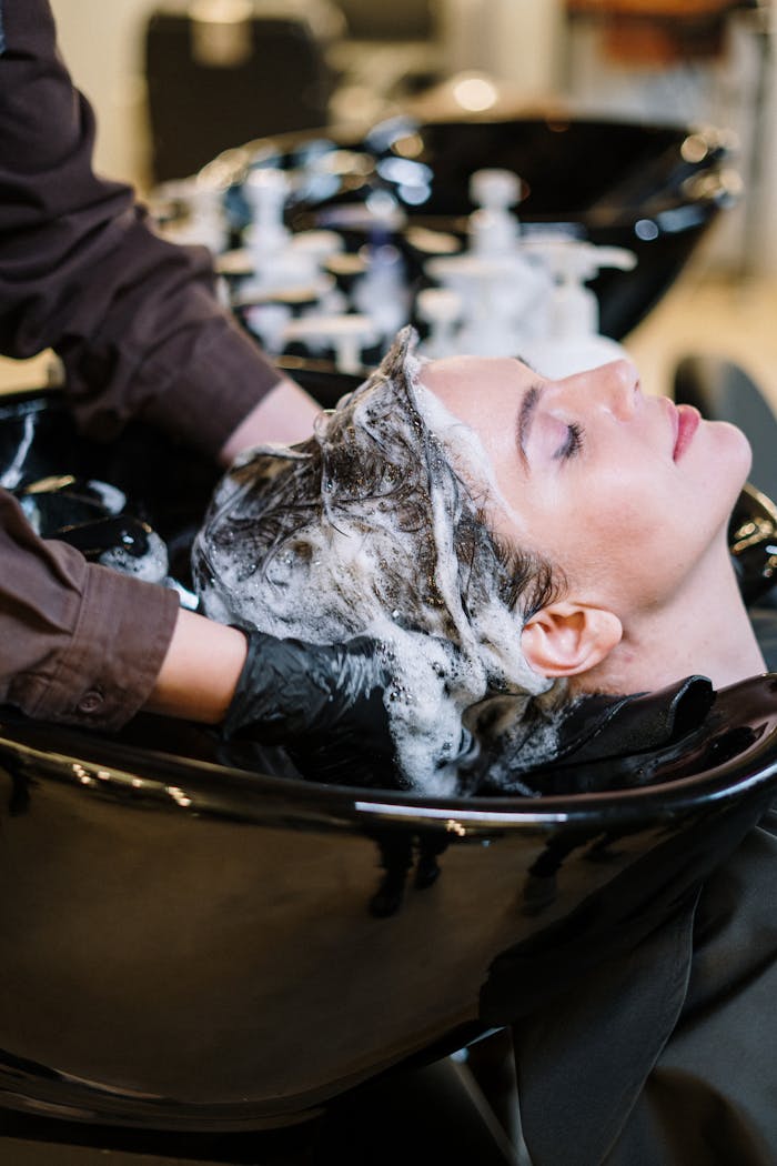 creative Professional hair stylist washing woman's hair in a modern salon setting.